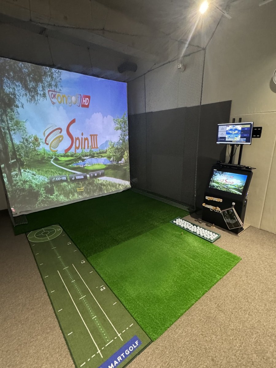 スマートゴルフの打席。スクリーンとシミュレーター、手前にパターマット